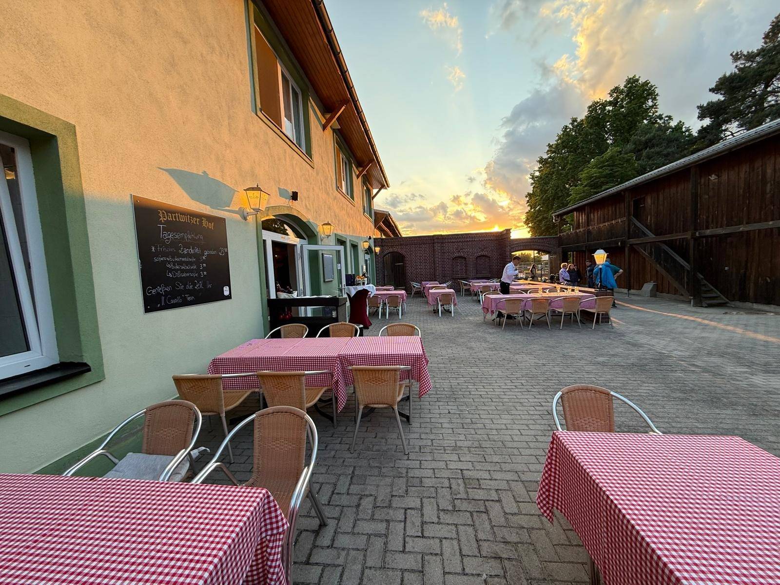 Courtyard terrace with red and white checked tablecloths in the evening light